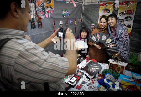 Téhéran, Iran. 12 Juin, 2014. Un visiteur prend des photos de sa femme et le chinois exhibitioners pendant le Salon International de l'Artisanat Exposition à Téhéran, capitale de l'Iran, le 12 juin 2014. © Ahmad Halabisaz/Xinhua/Alamy Live News Banque D'Images