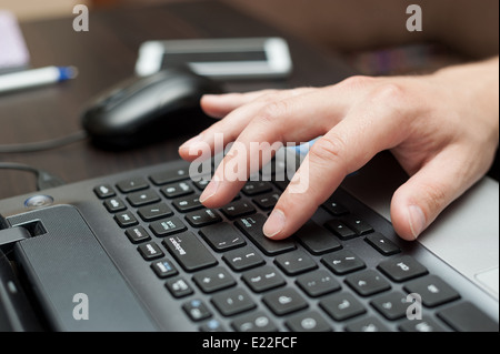 Main de l'homme blanc la touche Entrée sur un clavier d'ordinateur portable Banque D'Images