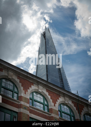 Un grand angle de l'Écharde de Londres contre un ciel bleu et blanc, avec l'immeuble en briques avec des fenêtres en premier plan Banque D'Images