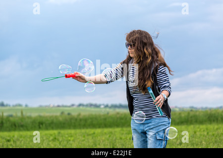 Belle Jeune femme font souffler des bulles, sur l'herbe verte Banque D'Images