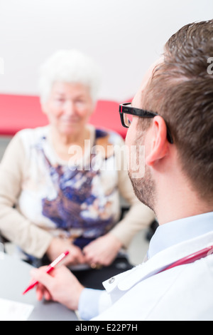 Médecin retraité assis avec consultation de chirurgie en heure à 24 Banque D'Images
