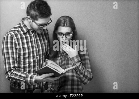 Jeune couple en vêtements et lunettes hippie chic en lisant un livre. studio shot Banque D'Images