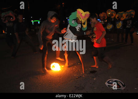 Solo, en Indonésie. 14 Juin, 2014. SOLO, le centre de Java, INDONÉSIE - JUIN 12 : Indonesian Men playing football fire .Â pendant l'attente pour l'ouverture de la Coupe du Monde de la FIFA, brésil 2014, en solo, le centre de Java, en Indonésie, le 12 juin. Fire est un jeu de football joué avec une boule de feu de coco, imbibé de kérosène en feu. © Agoes Rudianto/NurPhoto ZUMAPRESS.com/Alamy/Live News Banque D'Images