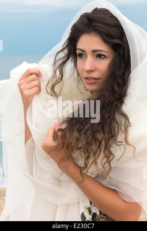 Belle jeune femme avec de longs cheveux noirs enveloppé dans une écharpe blanche Banque D'Images