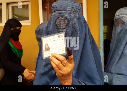 Une femme afghane en burqa traditionnelle montrer sa carte de vote et les doigts à l'encre après avoir voté le 14 juin 2014 à Kunduz, Afghanistan. Les Afghans à choisir un nouveau president pour remplacer le chef sortant Hamid Karzaï. Banque D'Images