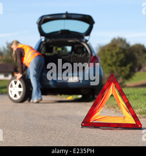 Voiture en panne avec un triangle d'avertissement rouge Banque D'Images