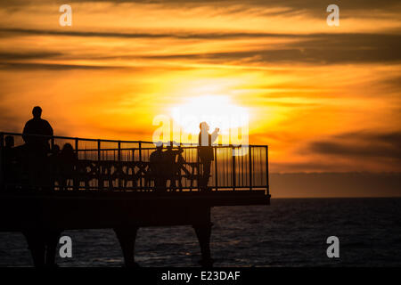 Pays de Galles Aberystwyth UK, 14 juin 2014 à la fin d'une belle journée d'été de presque unbroke le soleil et des températures dans les années 20 celsius, un homme photographies le coucher de soleil sur la jetée à Aberystwyth, sur la côte ouest du pays de Galles, UK Crédit photo : Keith morris/Alamy Live News Banque D'Images