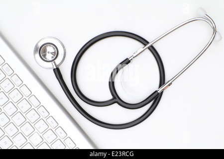 Stéthoscope isolé sur fond blanc avec un clavier d'ordinateur moderne Banque D'Images