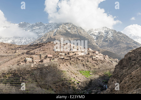 Village berbère perché précairement sur le versant aride, aride, en terrasses de montagne dans la vallée dans le Parc National du Toubkal, montagnes du Haut Atlas, Maroc Banque D'Images