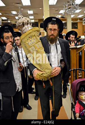 Les hommes juifs religieux portent la Torah retour à l'arche sacrée au cours matin services à la synagogue Loubavitch dans NYC Banque D'Images