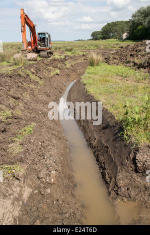 À l'aide d'un digger excavator pour la restauration de l'habitat travaux sur Deepdale Marsh, Burnham Deepdale, North Norfolk. Banque D'Images