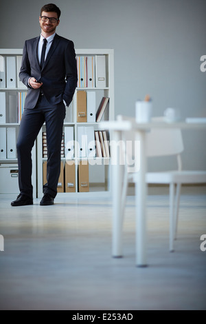 Handsome businessman en costume et lunettes looking at camera in office Banque D'Images