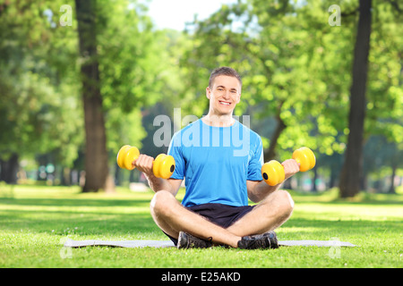 Homme travaillant sur le parc dans l'herbe sur assis sur un tapis de l'exercice Banque D'Images