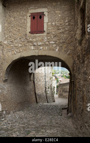 Une étroite ruelle pavée, Rue St François, descend de la tour de Crest à la vieille ville, en passant sous une voûte médiévale. La Drôme, France. Banque D'Images