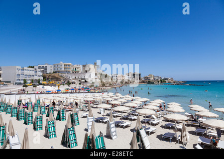 Des parasols de plage et des chaises longues sur une plage ensoleillée à Otranto, Pouilles, Salento région du sud de l'Italie Banque D'Images