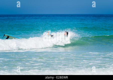 Un surfeur à St Ives, Cornwall, Angleterre, tombant de leur surf. Banque D'Images