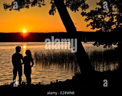 Bad Saarow, Allemagne. 12 Juin, 2014. Un jeune couple se dresse sur la rive du lac Scharmuetzelsee pendant le coucher du soleil à Bad Saarow, Allemagne, 12 juin 2014. Le lac Scharmuetzelsee est le plus grand lac de l'état allemand de Brandebourg et dit être le plus célèbre en Allemagne. Photo : Patrick Pleul/ZB/dpa/Alamy Live News Banque D'Images