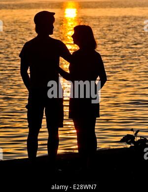 Bad Saarow, Allemagne. 12 Juin, 2014. Un jeune couple se dresse sur la rive du lac Scharmuetzelsee pendant le coucher du soleil à Bad Saarow, Allemagne, 12 juin 2014. Le lac Scharmuetzelsee est le plus grand lac de l'état allemand de Brandebourg et dit être le plus célèbre en Allemagne. Photo : Patrick Pleul/ZB/dpa/Alamy Live News Banque D'Images