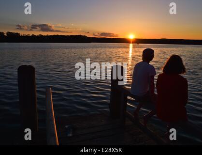 Bad Saarow, Allemagne. 12 Juin, 2014. Un jeune couple est assis sur une jetée au lac Scharmuetzelsee pendant le coucher du soleil à Bad Saarow, Allemagne, 12 juin 2014. Le lac Scharmuetzelsee est le plus grand lac de l'état allemand de Brandebourg et dit être le plus célèbre en Allemagne. Photo : Patrick Pleul/ZB/dpa/Alamy Live News Banque D'Images