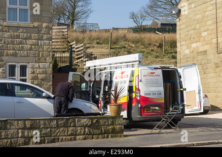 Of réparateur et van lors d'une visite à domicile, de travailler sur une voiture nécessitant un remplacement pare-brise. Banque D'Images