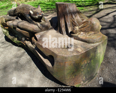 Fox et sculpture de lapin sur tronc d'arbre sculpté à la tronçonneuse banc de parc Banque D'Images