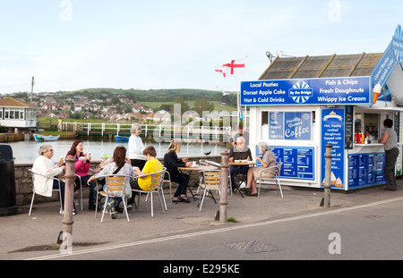 Les gens de manger du poisson et frites à un poisson et chip shop, West Bay, Port, Bridport Dorset Coast, England UK Banque D'Images