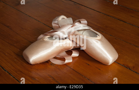 Nouvelle paire de chaussures de pointe avec des rubans pour le ballet sur un plancher de bois Banque D'Images