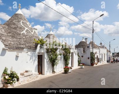 Scène de rue avec rangée de maisons traditionnelles blanchies à la chaux avec des toits coniques trulli à Alberobello, dans les Pouilles, Italie du sud Banque D'Images