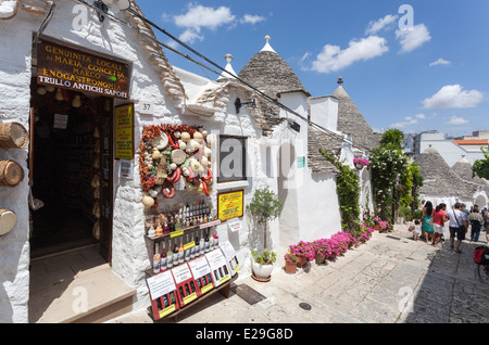 Boutique de souvenirs et de l'alimentation et la jolie scène de rue avec des bâtiments avec des toits coniques trulli à Alberobello, dans les Pouilles, Italie du sud Banque D'Images