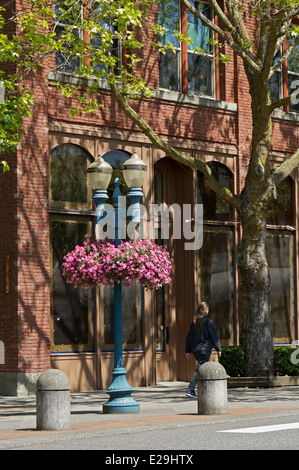 Femme marche passé un vieux bâtiment de brique dans le centre-ville de Bellingham, Washington State, USA Banque D'Images