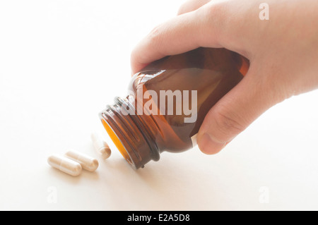 Capsules de verser une bouteille de pilules, l'accent sur le cou de bouteille Banque D'Images