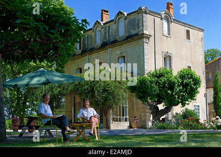 La France, l'Hérault, Saint Aunes, Château les Mazes domaine, couple assis sur des chaises dans un jardin en face d'une maison, les propriétaires Banque D'Images