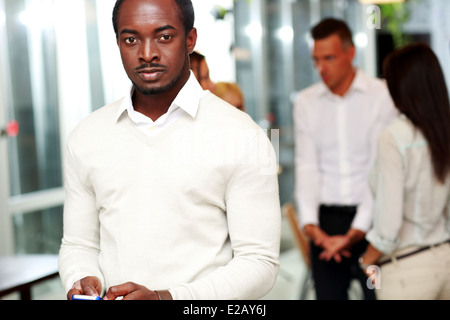 Portrait of a businessman using smartphone et à la caméra au devant des collègues Banque D'Images