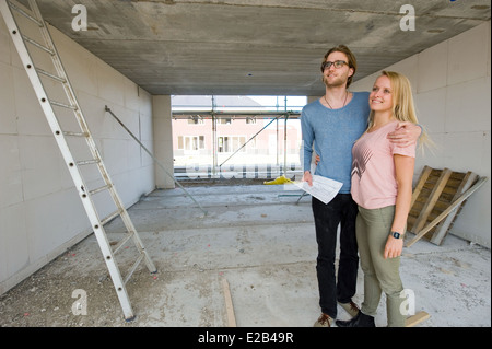 Jeune couple avec blueprint est à leur nouvelle maison heureusement comment se construit. Banque D'Images