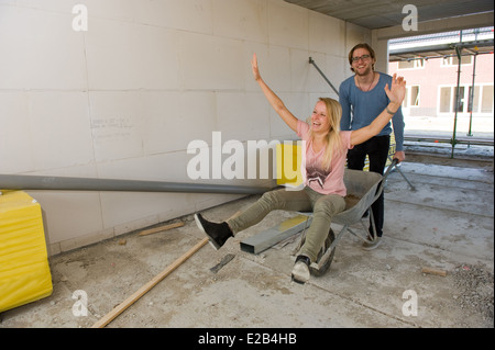 Jeune couple est heureux et s'amusant avec une brouette dans leur nouvelle maison Banque D'Images