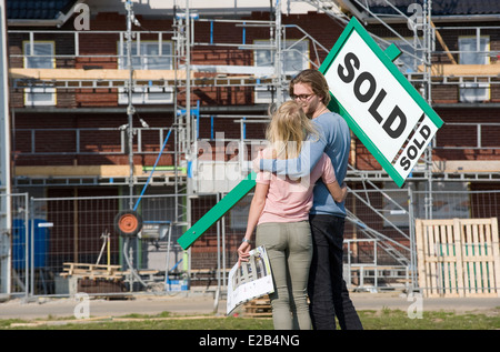 Jeune couple avec blueprint est heureux devant leur nouvelle maison construite ils juste acheté, Banque D'Images