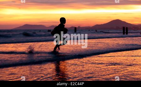 Sanya, province de Hainan en Chine. 18 Juin, 2014. Un enfant joue sur le bord de la mer au coucher du soleil à Sanya, province de Hainan en Chine du sud, le 18 juin 2014. Crédit : Chen Wenwu/Xinhua/Alamy Live News Banque D'Images