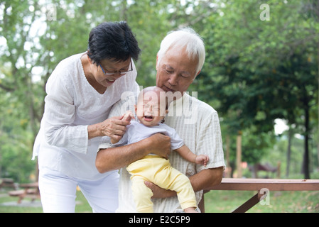 Les grands-parents asiatiques réconfortant crying baby grandson at outdoor Banque D'Images