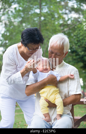 Les grands-parents asiatiques réconfortant crying baby grandson at outdoor Banque D'Images