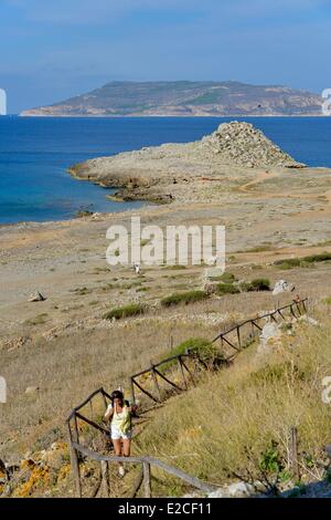 L'Italie, la Sicile, les îles Egadi, île de Favignana, Pointe, Borgo Italia 77 jeune femme sur un chemin de randonnée menant à la grotte de Uccerie avec l'île de Levanzo dans l'arrière-plan Banque D'Images