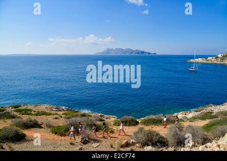 L'Italie, la Sicile, les îles Egadi, l'île de Levanzo, Cala Fredda, marcheurs sur un sentier surplombant la mer avec l'île de Favignana dans l'arrière-plan Banque D'Images