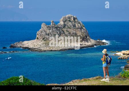 L'Italie, la Sicile, les îles Egadi, l'île de Levanzo, randonneur sur un sentier côtier avec vue sur mer avec Borgo Italia 77 île en arrière-plan Banque D'Images