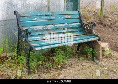 Banc de jardin patiné avec envahis par les mauvaises herbes Banque D'Images