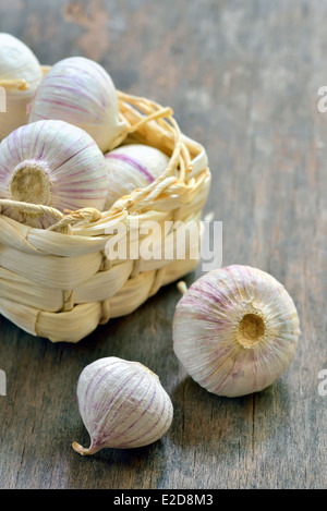 L'ail violet frais dans un petit panier de paille sur la vieille table en bois Banque D'Images