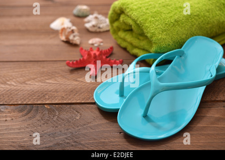 Les tongs bleu avec étoile de mer rouge et la serviette sur fond de bois Banque D'Images