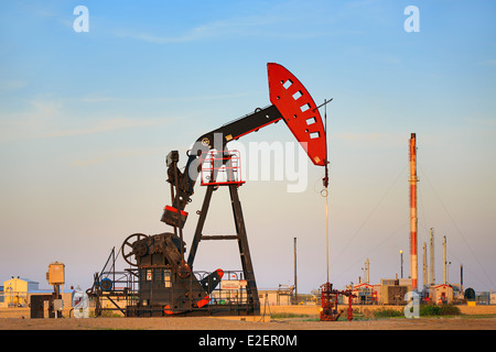 Pompe de puits de pétrole jack, avec l'usine à gaz naturel liquide en arrière-plan, près d'Estevan, Saskatchewan, Canada Banque D'Images