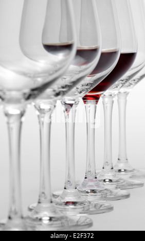 Quelques verres de vin consécutive permanent dans une rangée en gris clair, on partiellement rempli de vin rouge Banque D'Images