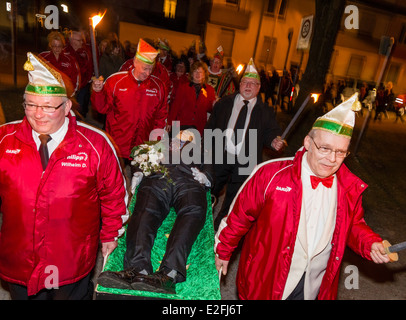 Carnaval allemand carnavaliers dans la bonne humeur transporter le défunt Bacchus à son inhumation crémation factice avec une procession aux flambeaux. Banque D'Images