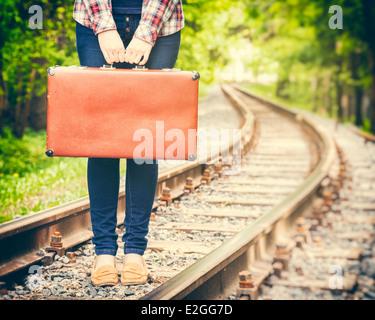 Fille avec retro vintage suitcase on railway, stylisé rétro Banque D'Images