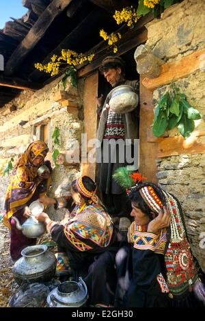 Le Pakistan Khyber Pakhtunkhwa vallées Kalash Kalash valley Bumburet famille offrant du lait pour une petite fille musulmane avant d'entrée d'étable fleuri de manches pour rite de fleurs jour et de lait dans les célébrations des préludes Joshi spring festival Banque D'Images